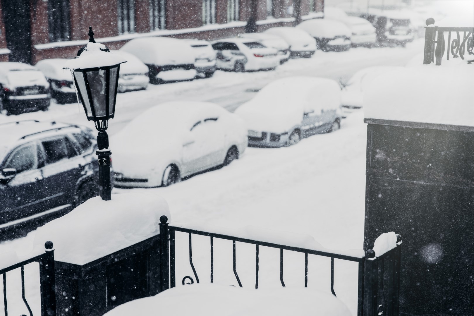 Cars covered with snow in parking lot. Street after heavy snowstrom.