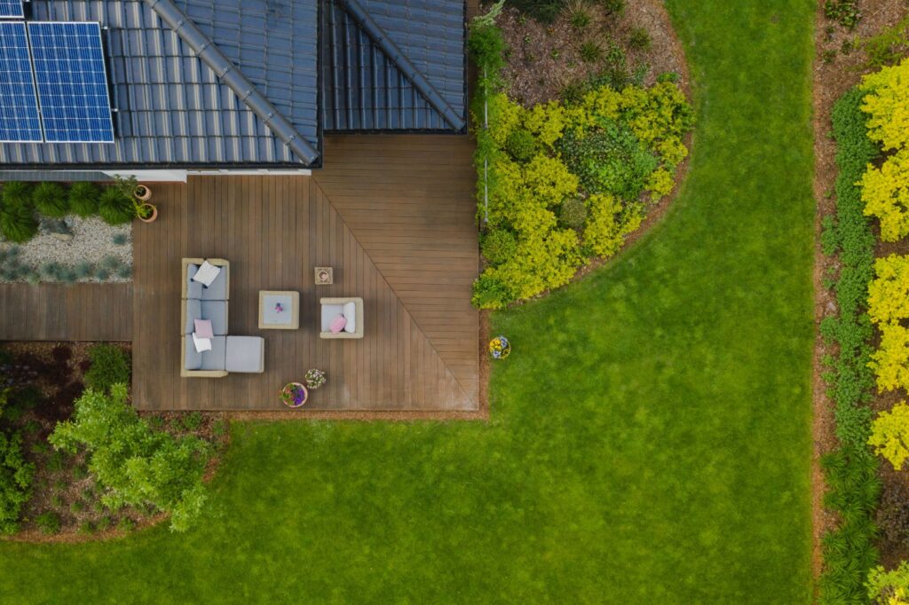 Top view of suburban house with green garden and wooden terrace